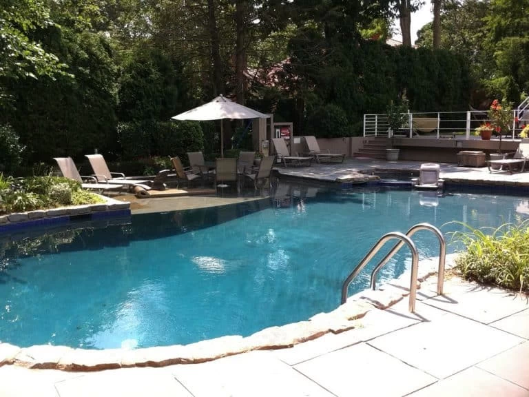 Swimming pool in a backyard with a lounge chair and umbrella providing a relaxing outdoor seating area