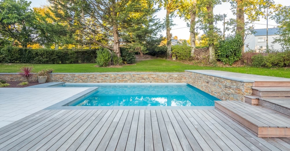 A wooden deck with a pool in the backyard.